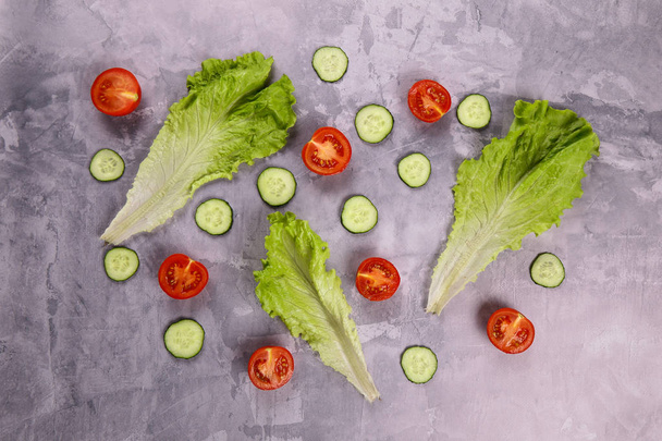 Surtido de verduras frescas. Tomates, pepinos y hojas de lechuga en una tabla de hormigón
 - Foto, imagen