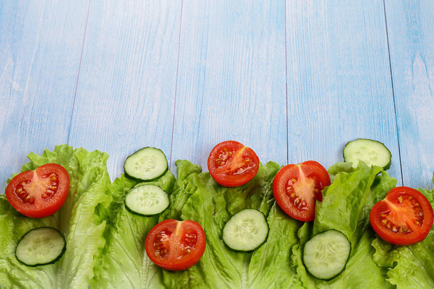 Assortment of fresh vegetables. Tomatoes, cucumbers and lettuce on a wooden background - Photo, Image