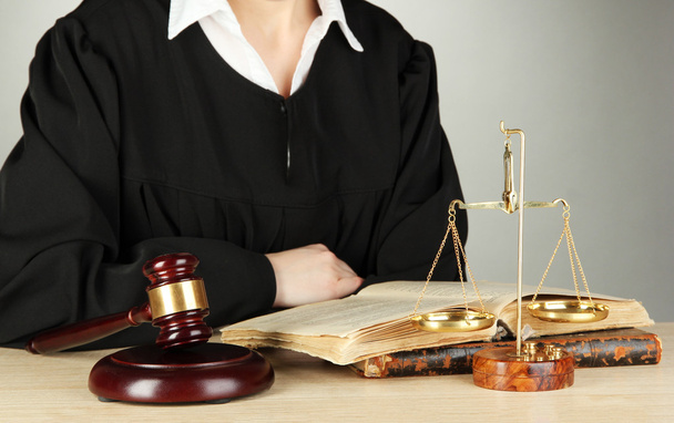 Судья сидит за столом во время судебных слушаний на сером фоне
 - Фото, изображение