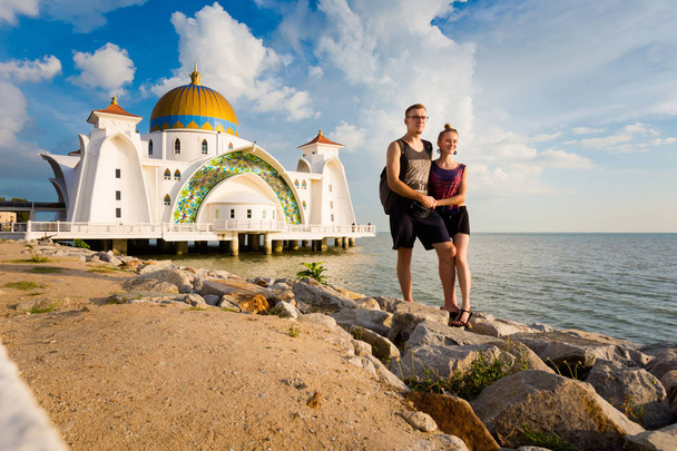 マレーシアのマラッカ市街マラッカ海峡モスクの観光客のカップル。東南アジアの美しい仙骨建物. - 写真・画像