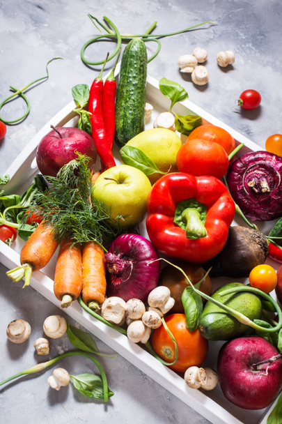 Rauwe biologische groenten met verse ingrediënten voor gezond koken in witte lade op concrete achtergrond. - Foto, afbeelding