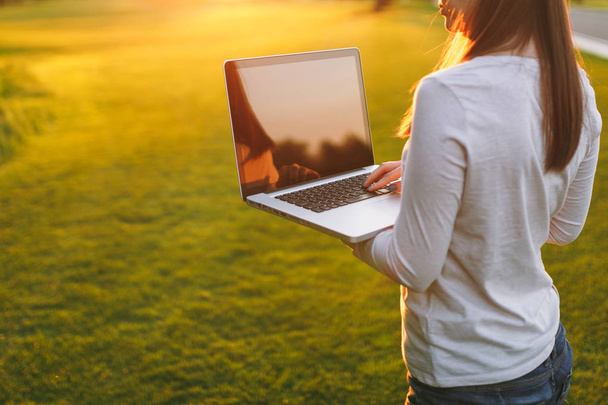 Hände auf der Tastatur. Frau arbeitet am Laptop PC-Computer mit leeren schwarzen leeren Bildschirm, um Platz im Park auf grünem Rasen Sonnenschein Rasen im Freien zu kopieren. mobiles Büro. freiberufliches Geschäftskonzept - Foto, Bild