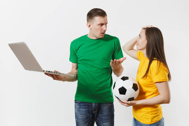 Geschocktes Ehepaar, Fußballfans in gelb-grünem T-Shirt feuern ihre Mannschaft mit Fußball an und verfolgen das Spiel auf dem Laptop isoliert auf weißem Hintergrund. Sport Familie Freizeit Lifestylekonzept - Foto, Bild