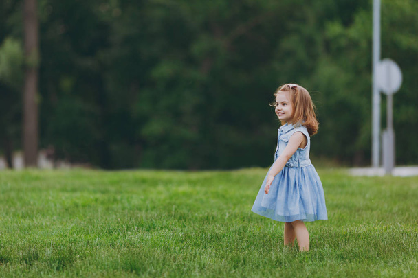Pretty little cute child baby girl in denim dress standing, play and have fun on green grass lawn in park. Mother, little kid daughter. Mother's Day, love family, parenthood, childhood concept - Foto, Bild