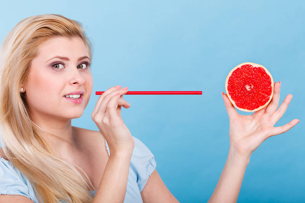 Healthy diet, refreshing food full of vitamins. Woman drinking juice from juicy fruit, redgrapefruit - Фото, изображение