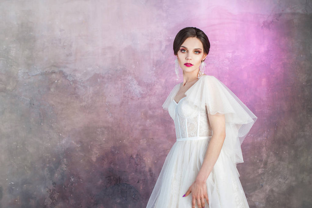 Beautiful and stylish bride in wedding dress in Studio on grey textured background - Zdjęcie, obraz