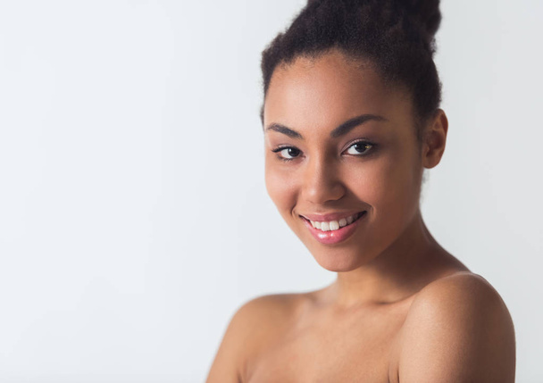 Menina afro-americana bonita está olhando para a câmera e sorrindo, isolado no branco
 - Foto, Imagem