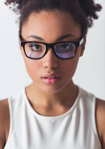 Retrato de una hermosa chica afroamericana en gafas mirando a la cámara, aislada en blanco
 - Foto, imagen