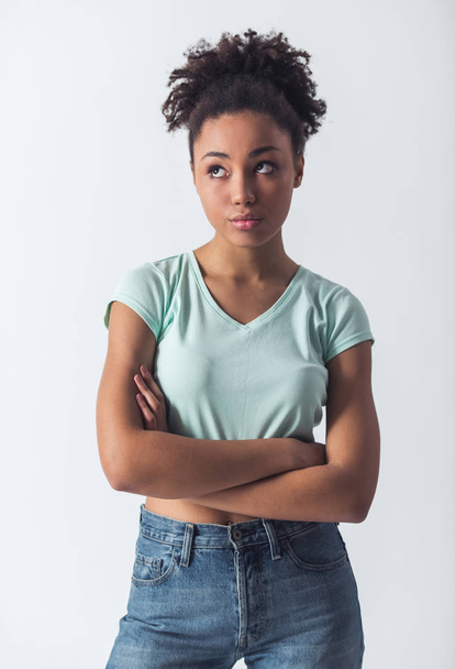 Pensive Afro-American girl in casual clothes is looking away and thinking, isolated on white - 写真・画像