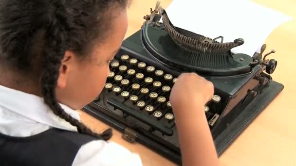 roztomilý afrických amerických školačka pomocí staromódní psací stroj - Záběry, video