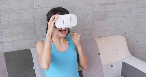 Возбужденная женщина наслаждается живым шоу с VR устройством дома
 - Фото, изображение