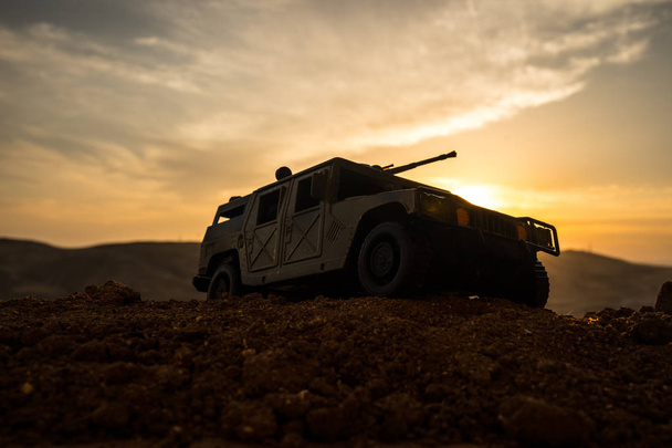 Katonai patrol car naplemente háttér. Hadsereg háború fogalmát. Sziluettjét a páncélozott jármű a fegyver akcióban. Díszített. Szelektív összpontosít - Fotó, kép