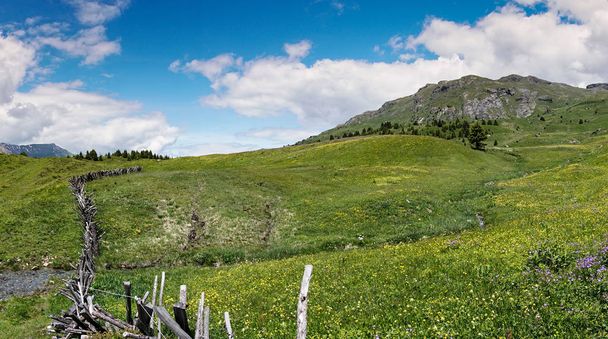 ідилічний гірський пейзаж в літній час з традиційним дерев'яним парканом на передньому плані
 - Фото, зображення