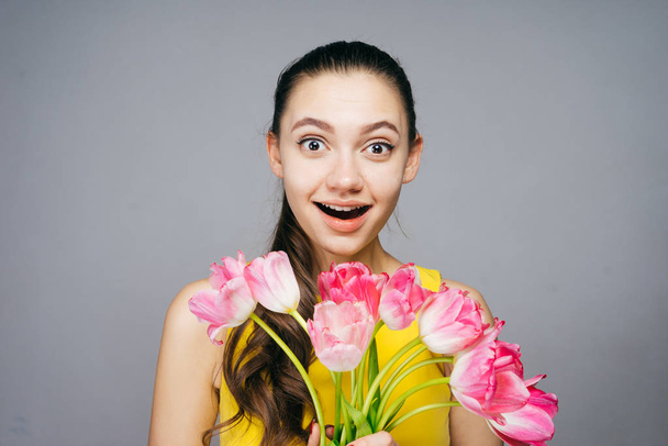 lovely surprised girl in a yellow dress received a bouquet of fragrant flowers for the holiday - Foto, Imagen