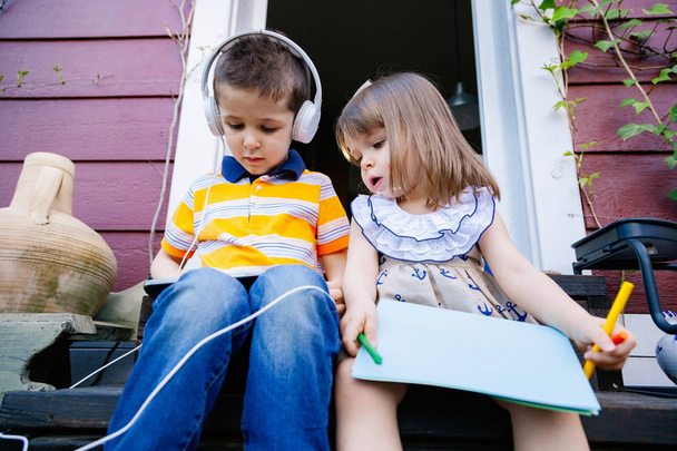 Irmãos ouvindo música com fones de ouvido do lado de fora
 - Foto, Imagem