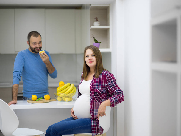 young pregnant couple cooking food fruit lemon juice at kitchen, lifestyle healthy pregnancy happy life concept - Fotografie, Obrázek