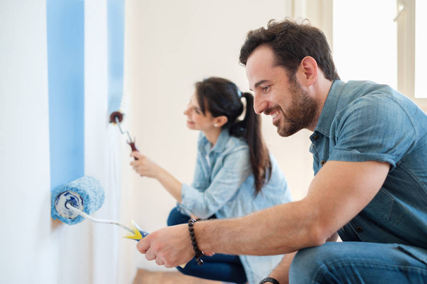 Paredes de pintura jovem casal em sua nova casa, fazê-lo sozinho conceito
 - Foto, Imagem