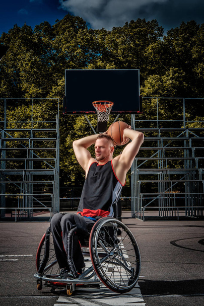 Verlamde basketbalspeler in een rolstoel speelt op een terrein van de open gaming. - Foto, afbeelding