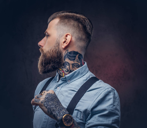 Profil eines gutaussehenden altmodischen Hipsters in blauem Hemd und Hosenträgern. isoliert auf dunklem Hintergrund. - Foto, Bild