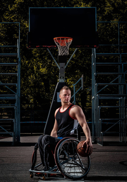 Retrato de un jugador de baloncesto discapacitado en una silla de ruedas en campo de juego abierto
. - Foto, imagen
