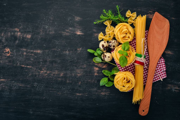 Italian cuisine. Dry pasta and basil. On a wooden background. Top view. Copy space. - Zdjęcie, obraz