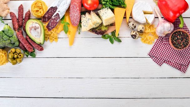 Assortment of sausage, cheese and fresh vegetables. On a white wooden background. Top view. Copy space. - Foto, Bild