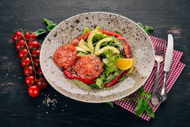Salad with avocado, tomato and fresh vegetables. On a wooden background. Top view. Copy space. - Foto, Bild