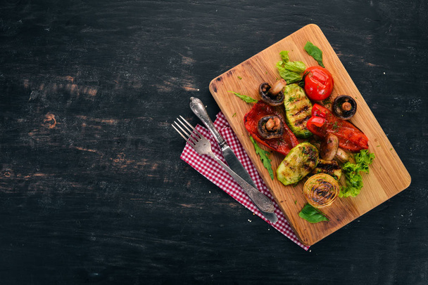 Grilled vegetables on a wooden board. On a wooden background. Top view. Copy space. - Foto, afbeelding