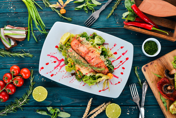 Salad with baked salmon and vegetables. On a wooden background. Top view. Copy space. - Fotografie, Obrázek