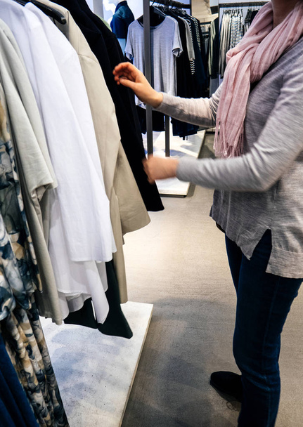 Vrouw winkelen voor mooie moderne kleding in casual winkel - Foto, afbeelding
