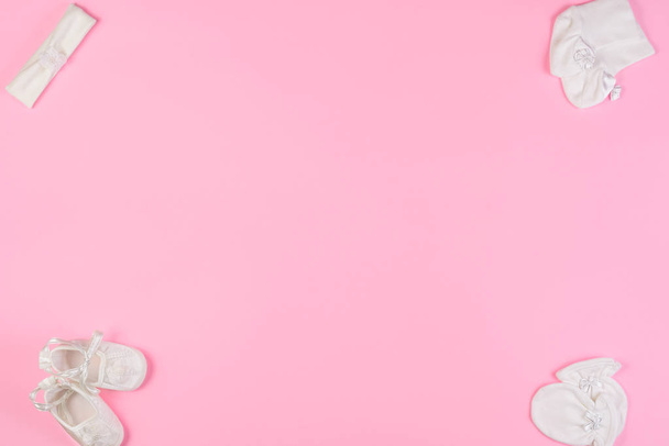 Bovenaanzicht van laarsjes voor de pasgeborene, baby sokken, handschoenen en Haarband op roze achtergrond. Ruimte voor tekst kopiëren. Bovenaanzicht. - Foto, afbeelding