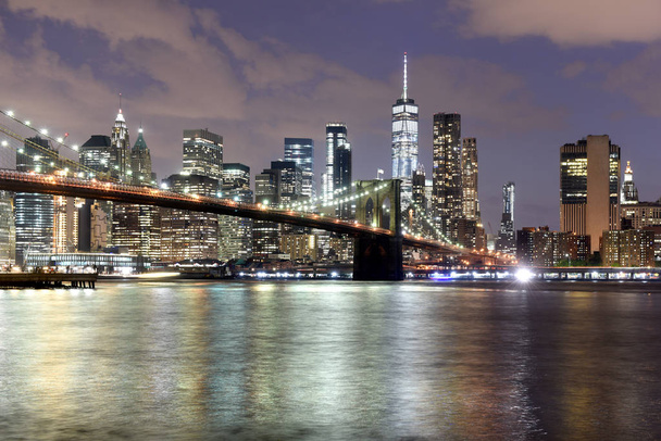 New York City, financial district in lower Manhattan with Brooklin Bridge at night, USA - Photo, Image