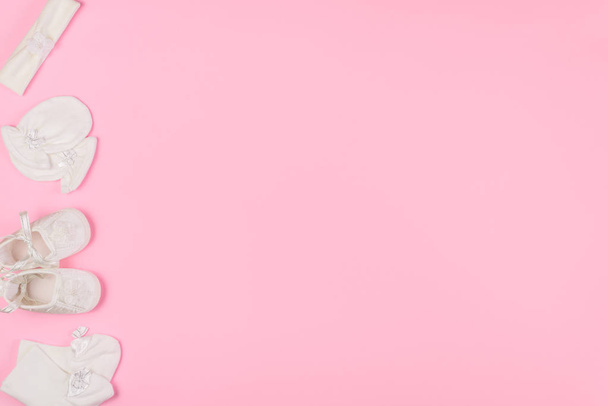 Vista superior de meias de bebê, luvas, faixa de cabelo e botas para recém-nascido em fundo rosa. Copiar espaço para texto. Vista superior
. - Foto, Imagem