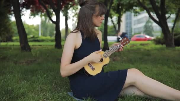 Young woman play on ukulele, little guitar - Кадри, відео