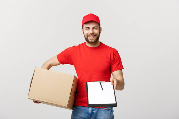 Delivery Concept: Young handsome delivery man with paper boxes giving you a document to sign - Φωτογραφία, εικόνα