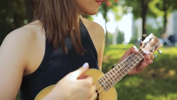 Young woman play on ukulele, little guitar - Materiał filmowy, wideo