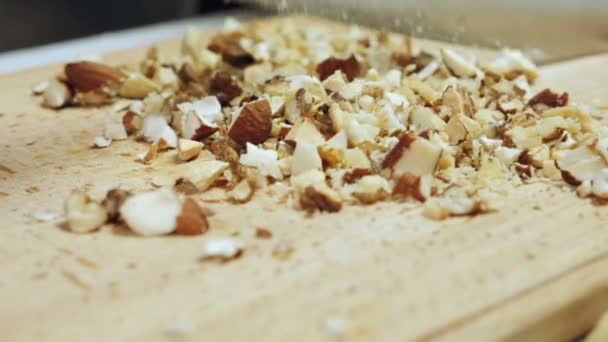 Chefs manos picando nueces mixtas en tabla de cortar de madera
 - Metraje, vídeo