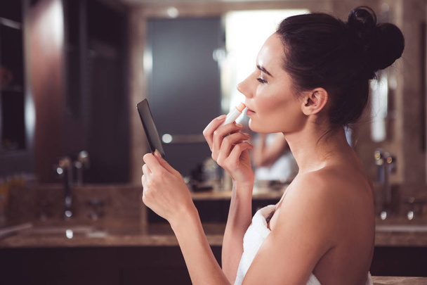 Young female with bump doing makeup before date - Foto, Imagen