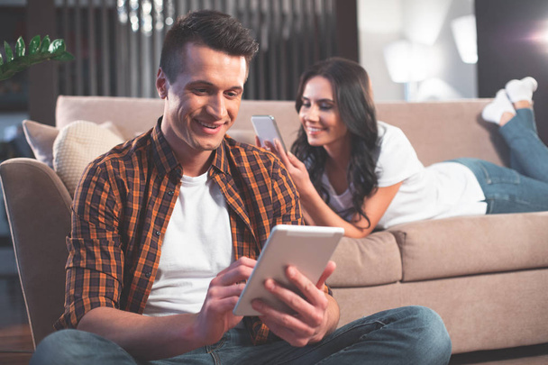 Cheerful married couple using tablet and smartphone  - Photo, image