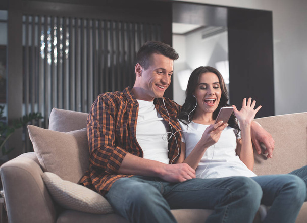 Joyful married couple using phone for online communication  - Zdjęcie, obraz