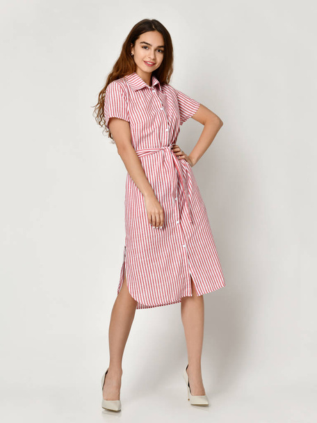 Young beautiful woman posing in new pink stripes casual summer dress on grey  - Fotografie, Obrázek