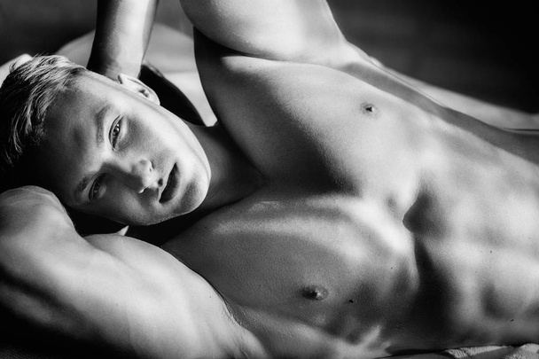 Güçlü sağlıklı yakışıklı atletik erkek yatakta poz portresi - Fotoğraf, Görsel