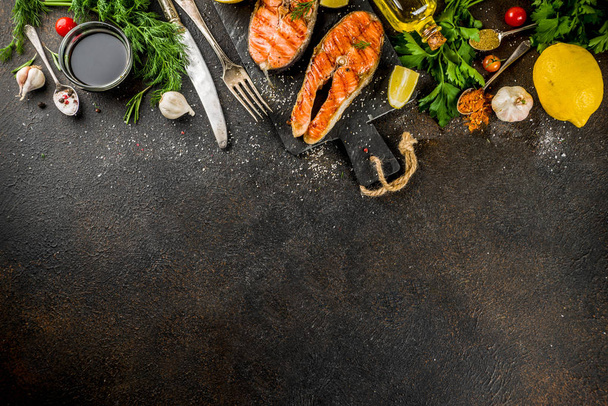 Filetes de salmón a la parrilla con ingredientes limón, hierbas, aceite de oliva, tabla de cortar pizarra, espacio de copia de fondo oscuro oxidado
 - Foto, imagen