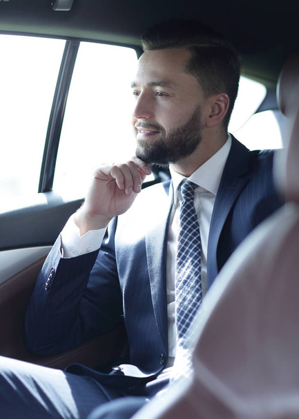 Smiling business man sitting in the back seat of a car - Fotografie, Obrázek
