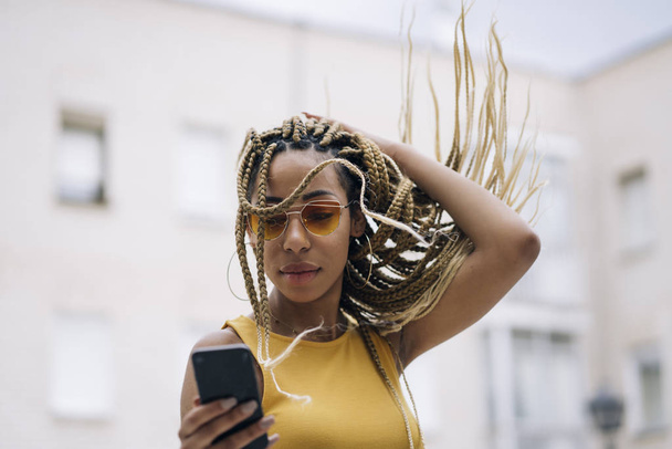 Afro-haired latin woman posing with mobile phone. - 写真・画像