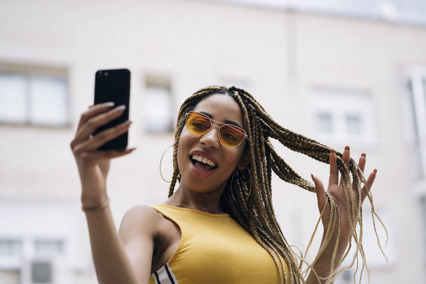 Afro-haired latin woman posing with mobile phone. - Photo, Image