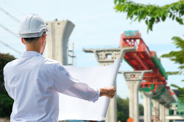 Architect working on blueprint.,engineer inspector in workplace. ,Engineers in helmets planning new project Laying the foundations of the train - Photo, Image