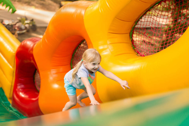 happy excited girl having fun on inflatable attraction playground.  - Photo, Image