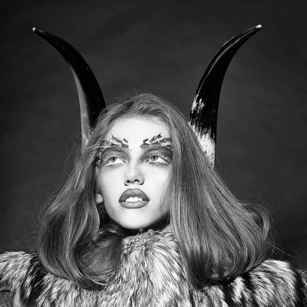 woman with make-up in the style of a demon. Girl with antlers and fur coat - Photo, image