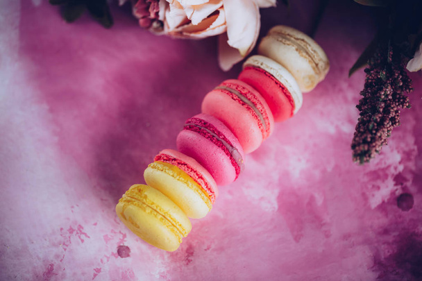 Row of cake macaroons on bright background. Close up macaron dessert on top view. Colorful almond cookies in pastel pink, yellow colors. Vintage toning style. - Φωτογραφία, εικόνα